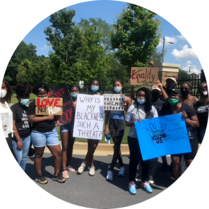 black activists holding signs reading "Love not hate", "Why is my blackness such a thread?", "BLM", "Equality", "Stop killing us"