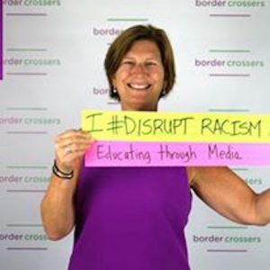 woman holding a sign reading I #Disrupt Racism Educating through Media