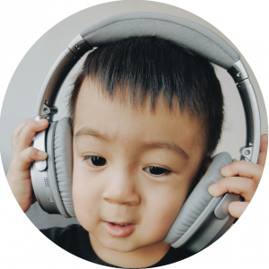 brown toddler adjusting closed-back headphones on head