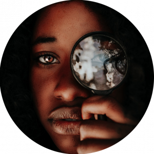 black woman holding magnifying glass up to her eye